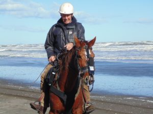 Figure 5b. Hanson in the saddle with his 11-year-old half-bred mare wearing his copy of a Bedouin noseband attached to the head collar supporting the exercise video-endoscope in the mare’s right nasal cavity. The audio-recorder lies above the white label. © 2015, Robert Cook, photo: Fridtjof Hanson